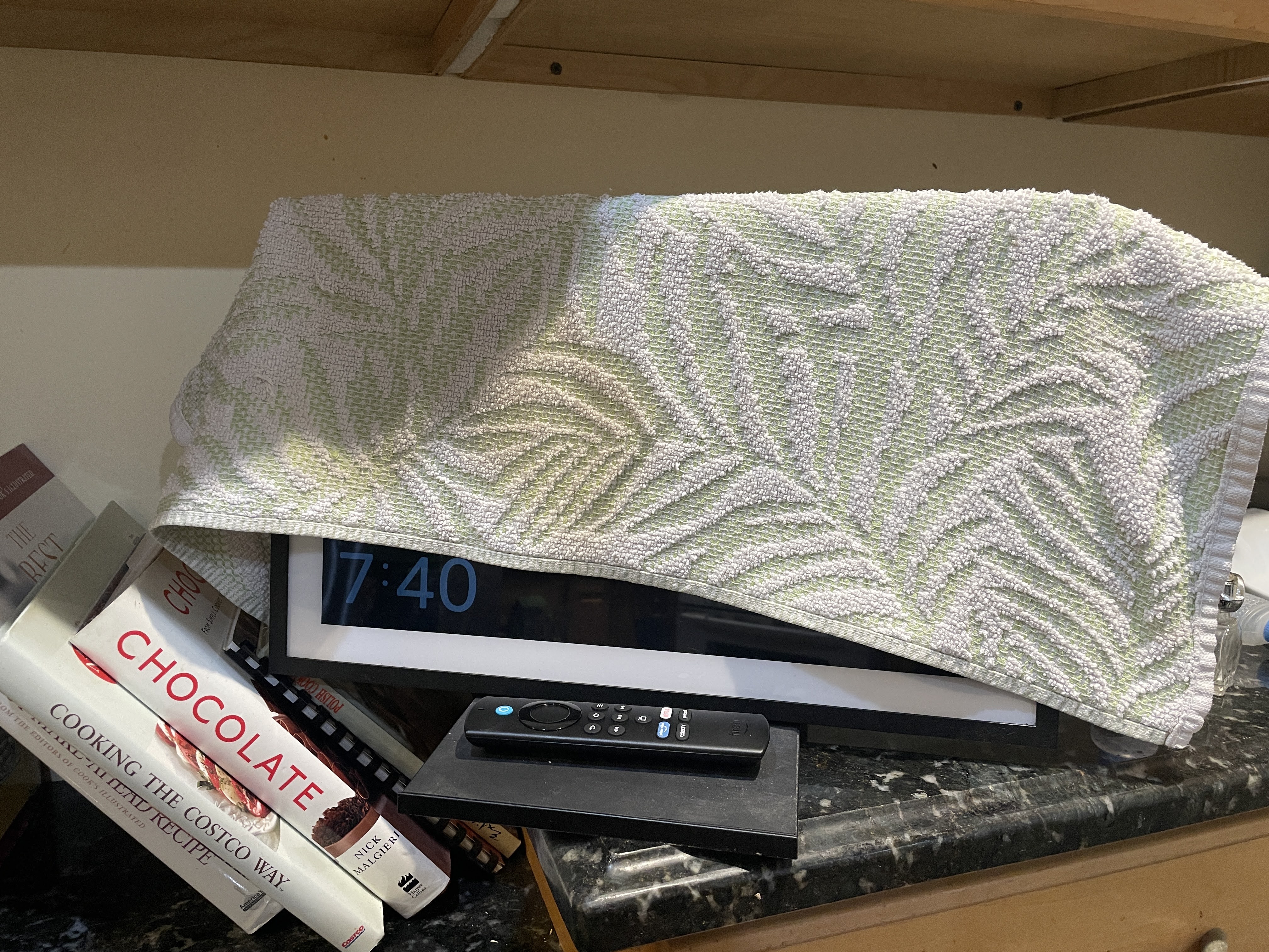 An &lsquo;Amazon Echo Show 15&rsquo; digital display with a hand towel thrown over most of the screen. The &lsquo;Sleep mode&rsquo; leaves a clock in the bottom left corner, which was left exposed with how the towel is draped over the device.