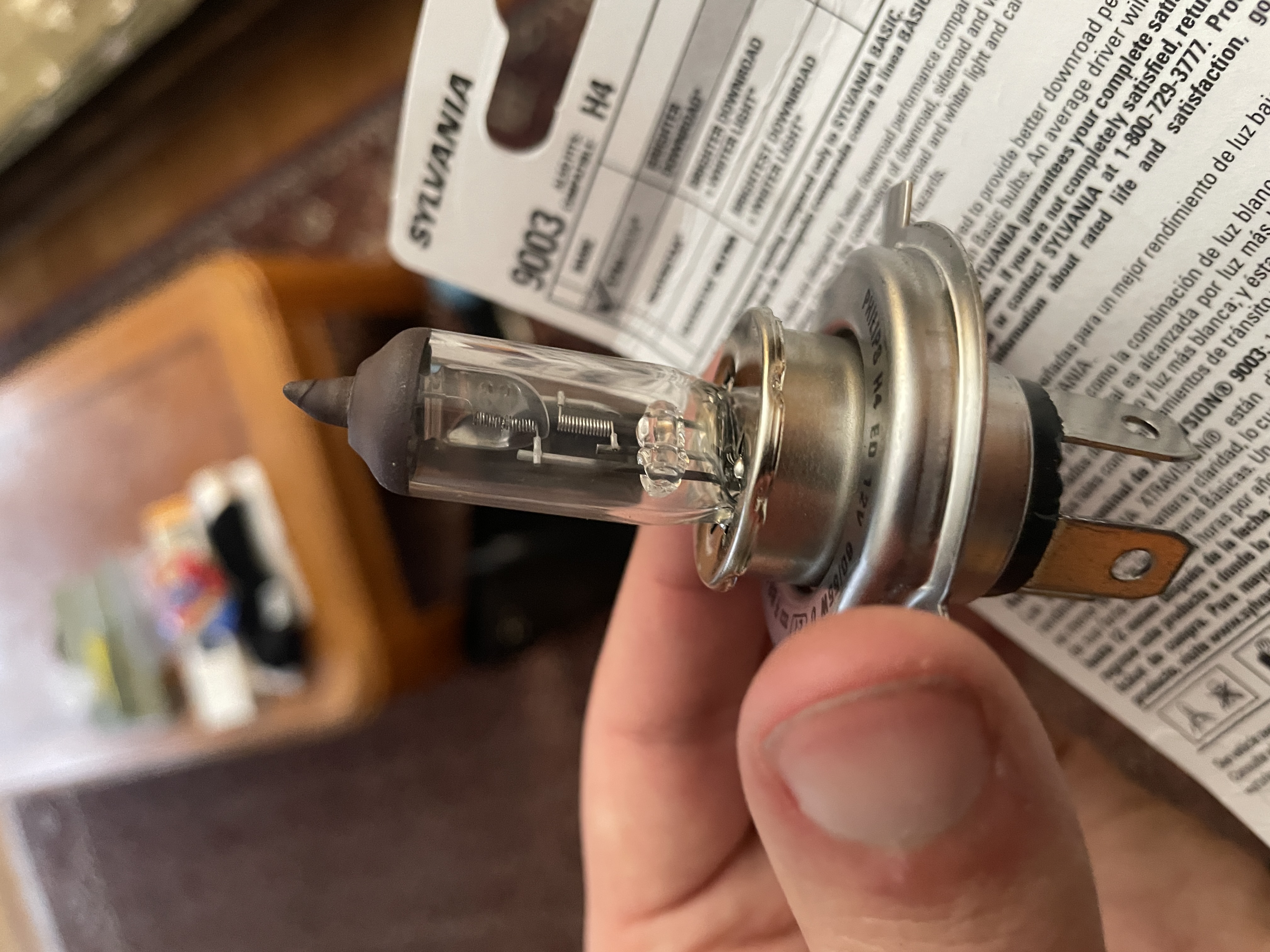 The Philips H4 bulb I took out of the bike, held in my hand. It has a burnt out filament.